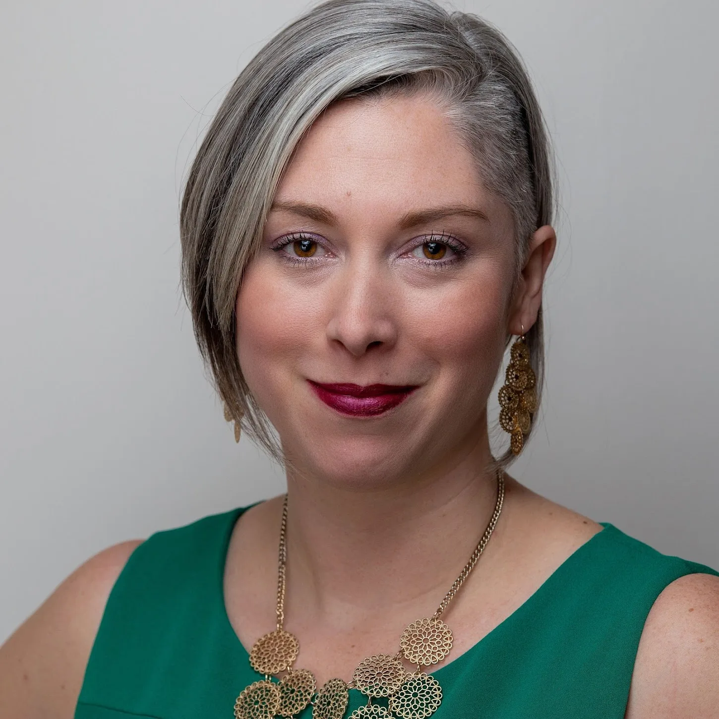 Alison Jamison wearing green dress with gold statement necklace