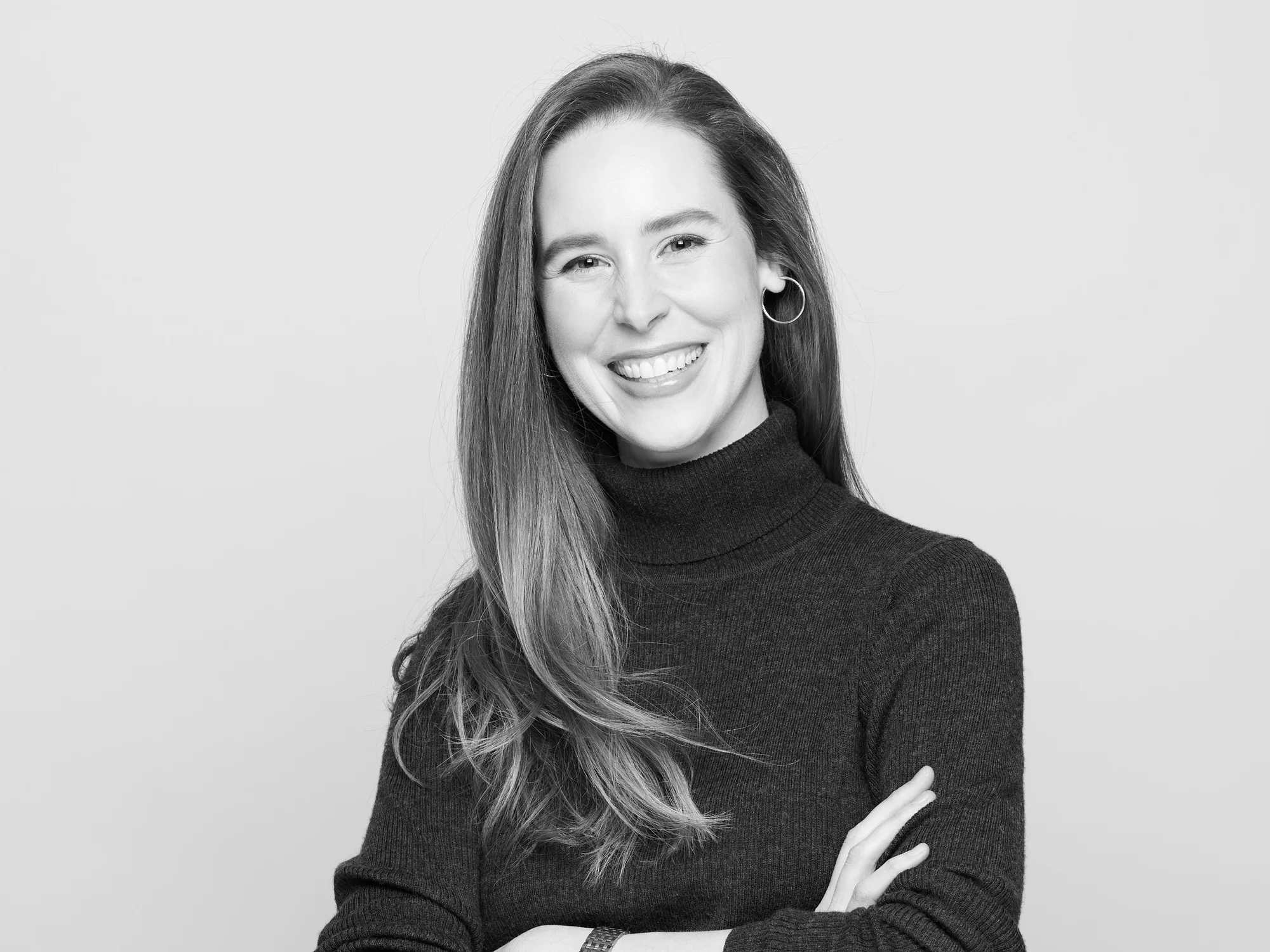 Professional headshot of woman in dark turtleneck with circular earrings