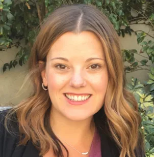 Mary Beth Ferrante smiling in front of green foliage