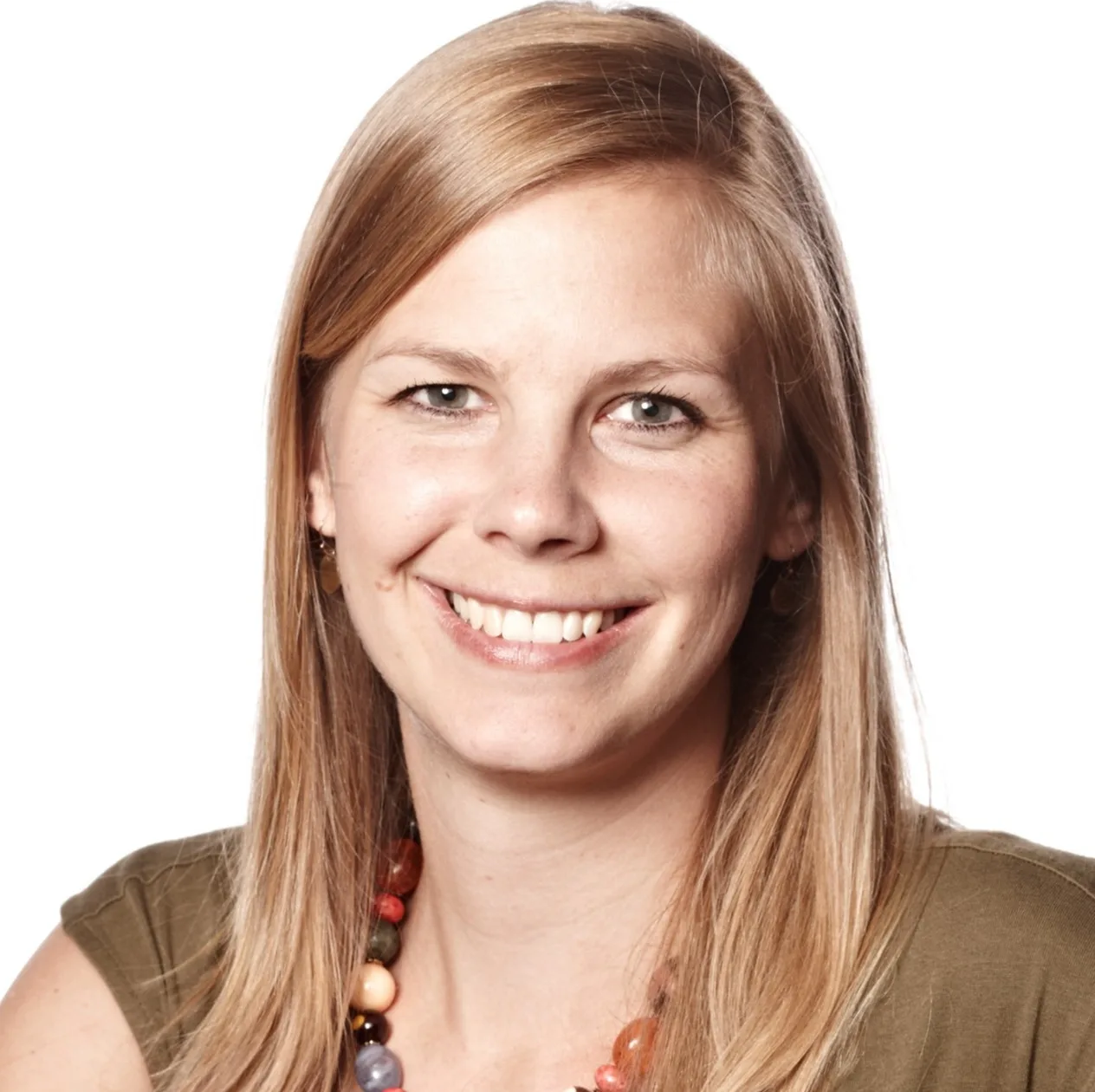 Woman with long blonde hair and beaded necklace smiling at camera