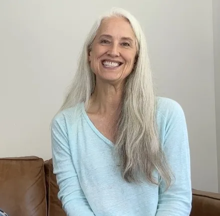 Megan Shave smiling in light blue sweater against white wall