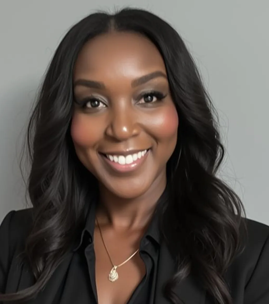 Smiling professional woman with long dark hair wearing black blazer and gold necklace