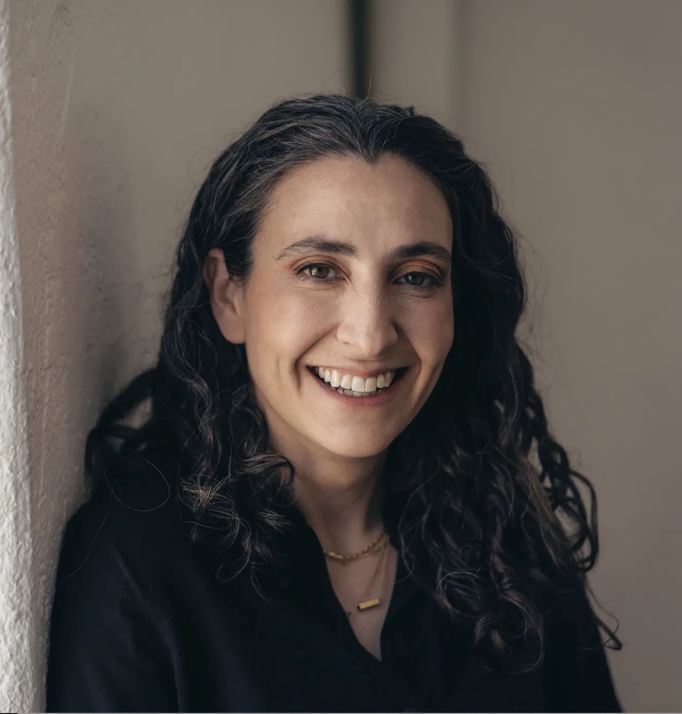 Woman with long curly dark hair smiling in professional portrait