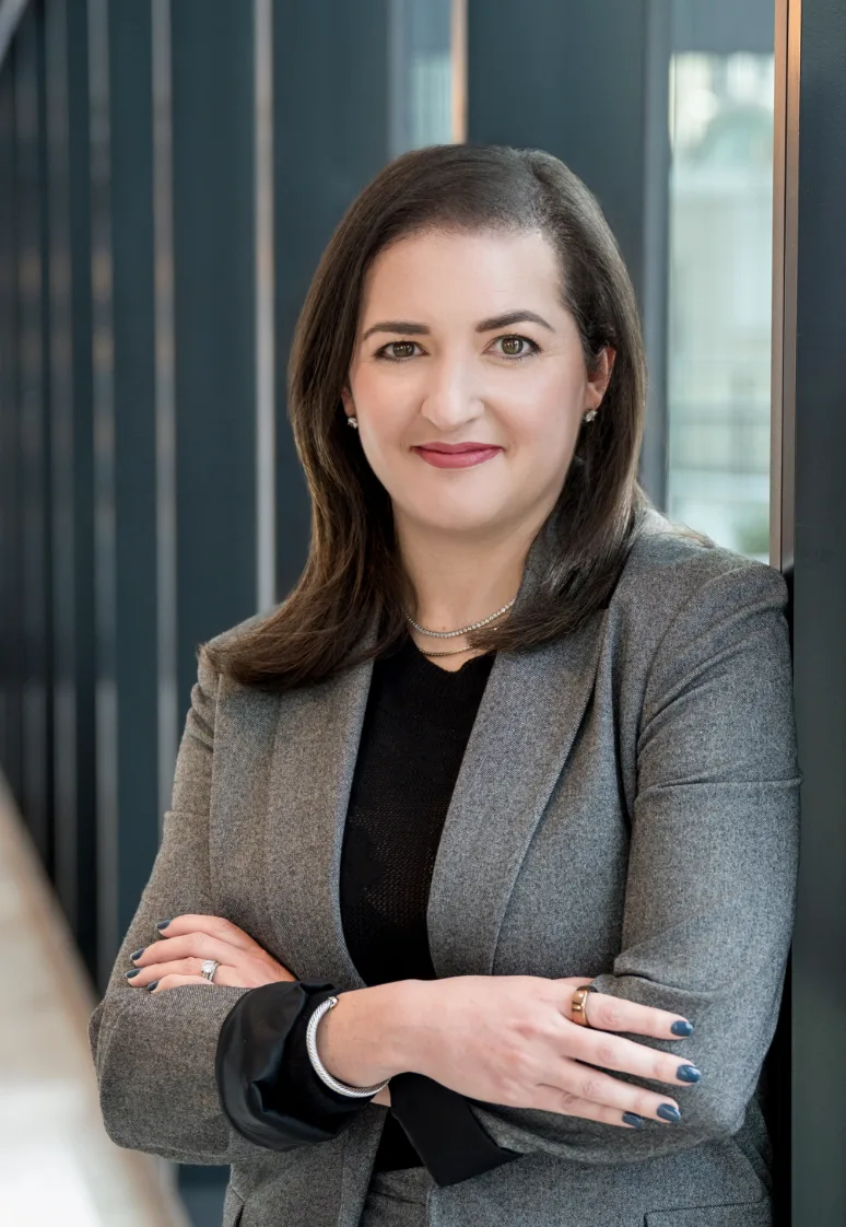 Professional woman in gray blazer and black top with arms crossed