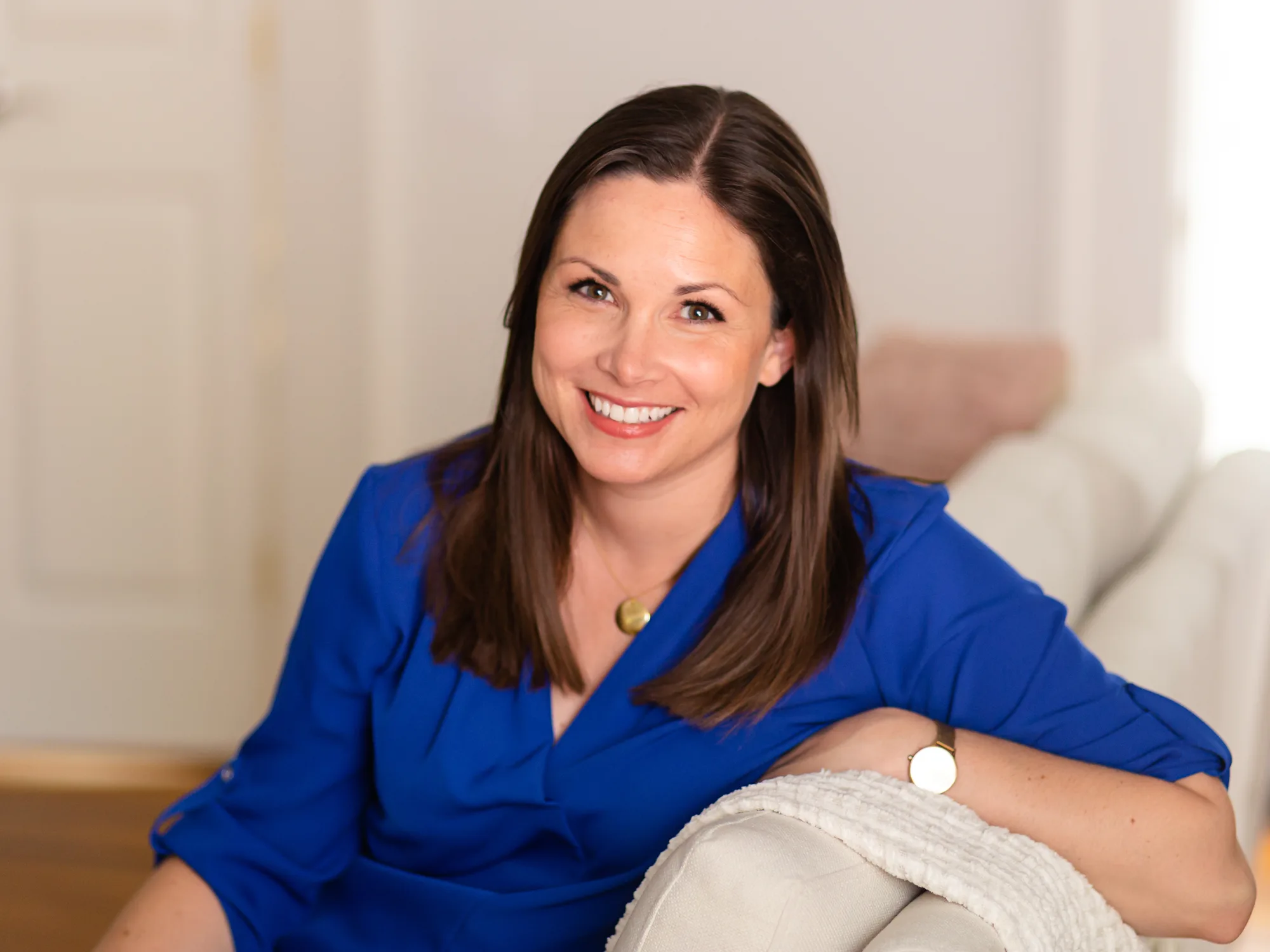 Woman in blue dress smiling at camera in bright, modern setting