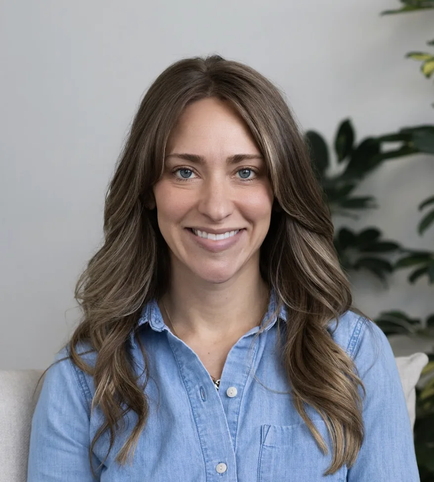 Smiling woman with long brown hair wearing light blue shirt