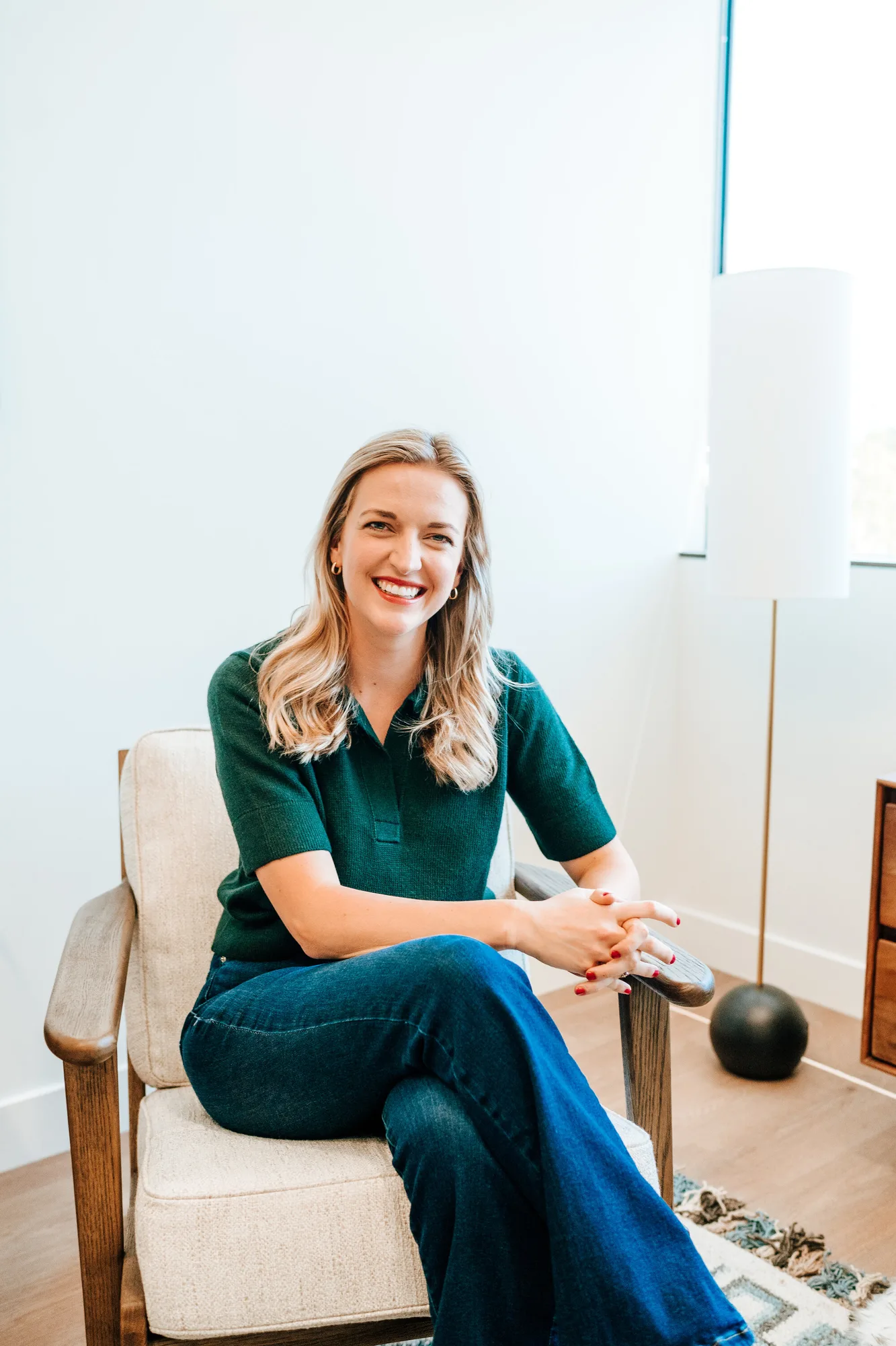 Woman in green polo shirt smiling while seated in modern chair