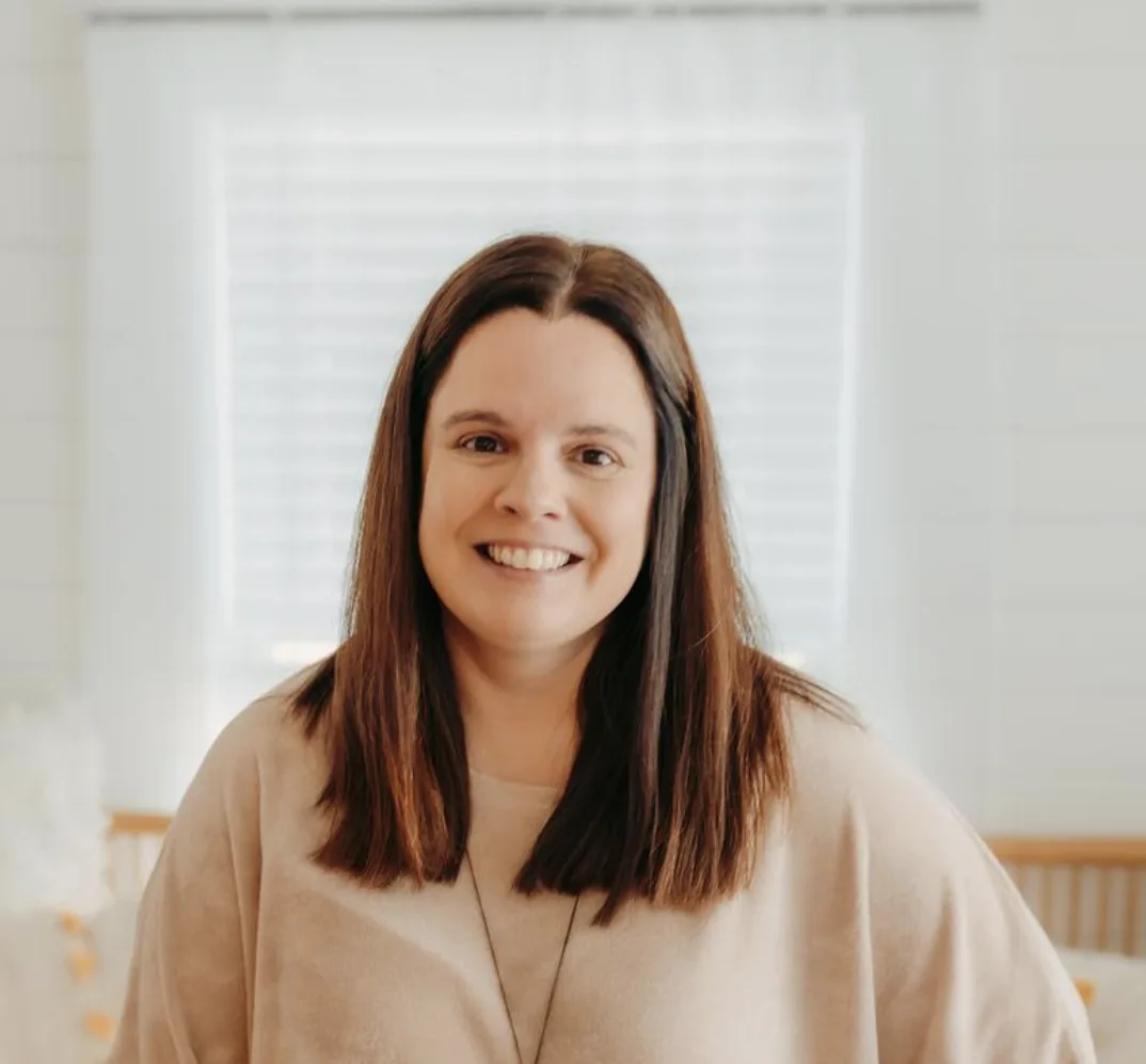 Smiling woman with long brown hair wearing a beige sweater