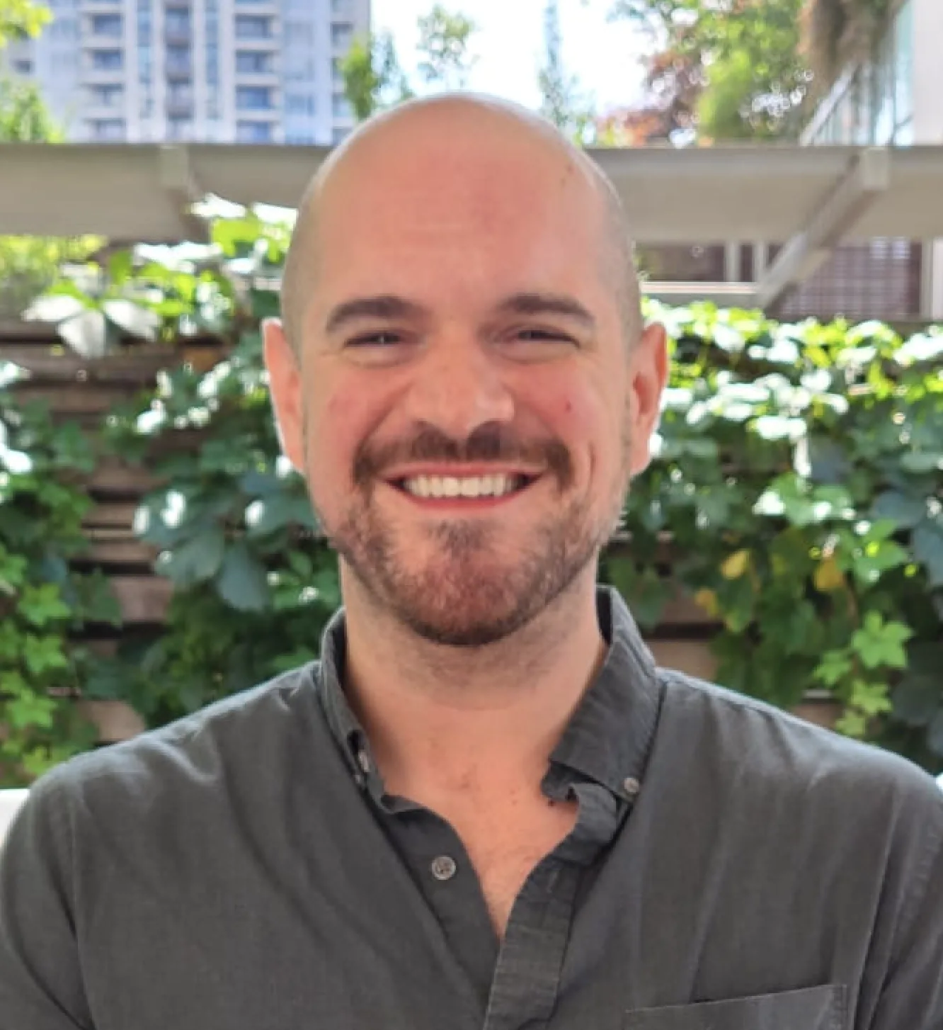 Smiling man with goatee in casual button-down shirt outdoors