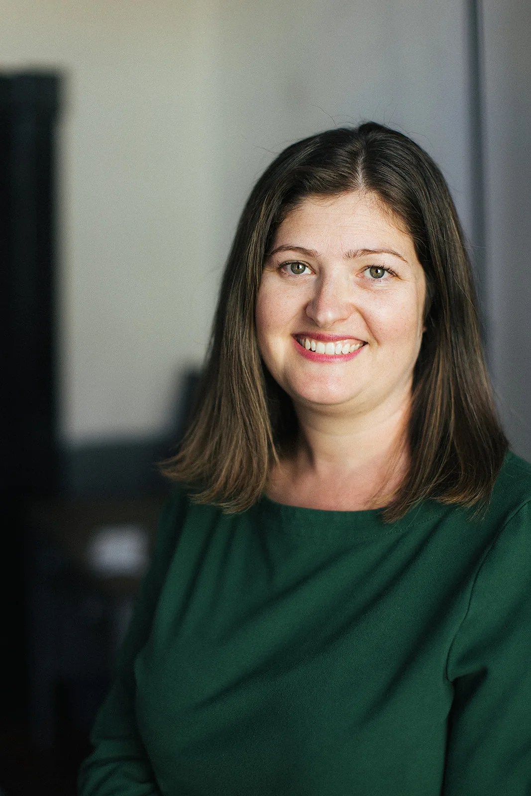 Professional portrait of woman with long brown hair wearing green top