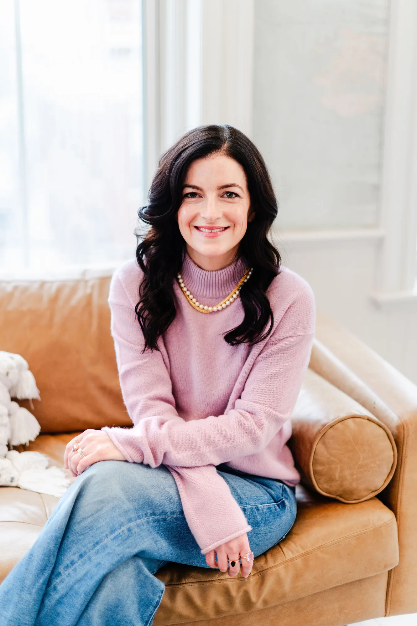 Woman with long dark hair wearing pink turtleneck sweater and gold necklace