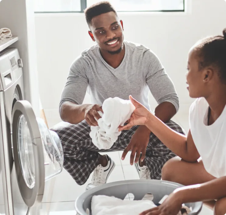 Father and son sorting white laundry together in front of washing machine